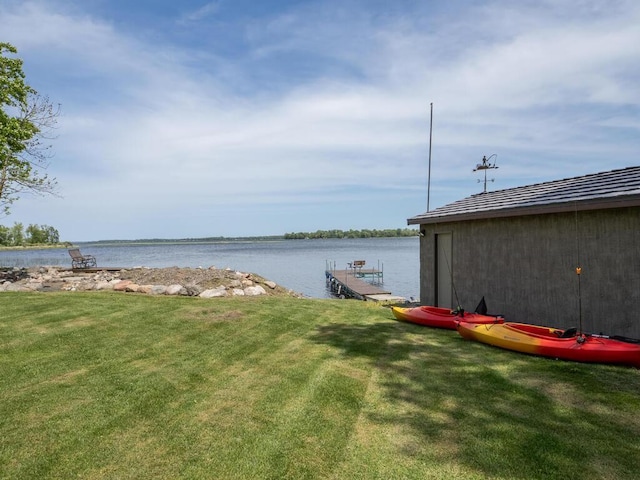 view of grassy yard featuring a water view and a dock
