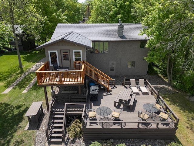 back of property with a deck, stairway, a lawn, and outdoor dining area
