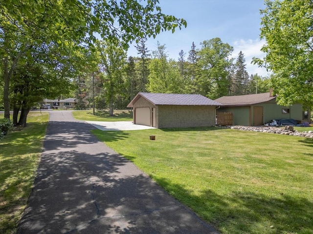 view of property exterior with asphalt driveway, a lawn, an outbuilding, and a chimney