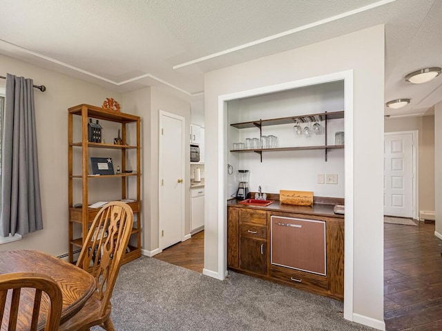 office space with dark carpet, bar, and baseboards