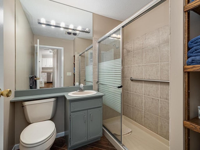 bathroom with a shower stall, vanity, and toilet