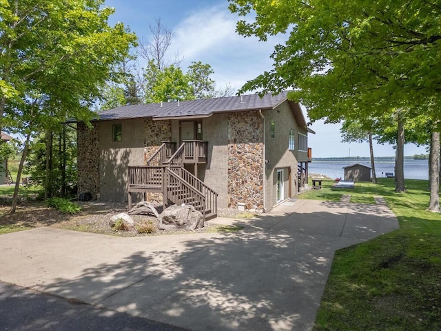 view of home's exterior featuring stone siding and a water view