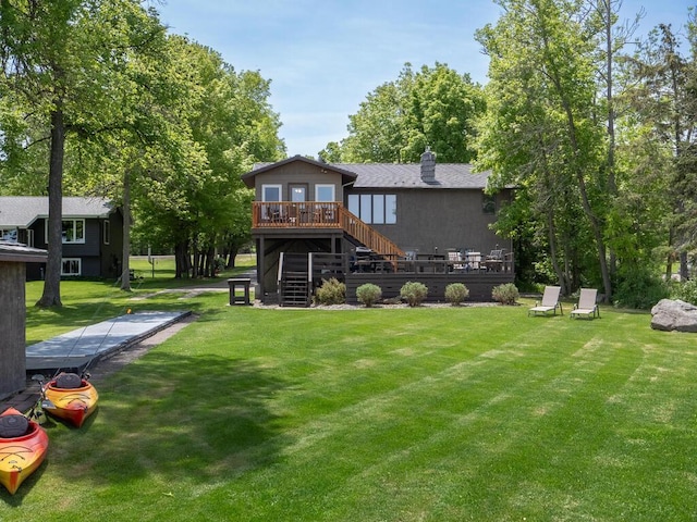 back of house featuring stairs, a deck, a chimney, and a lawn