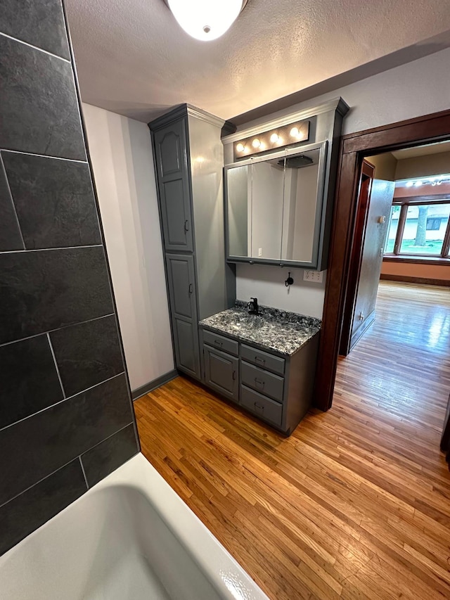 bathroom featuring vanity, a bathing tub, hardwood / wood-style floors, and a textured ceiling