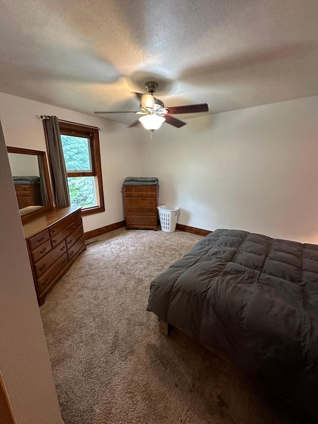 carpeted bedroom with ceiling fan and a textured ceiling