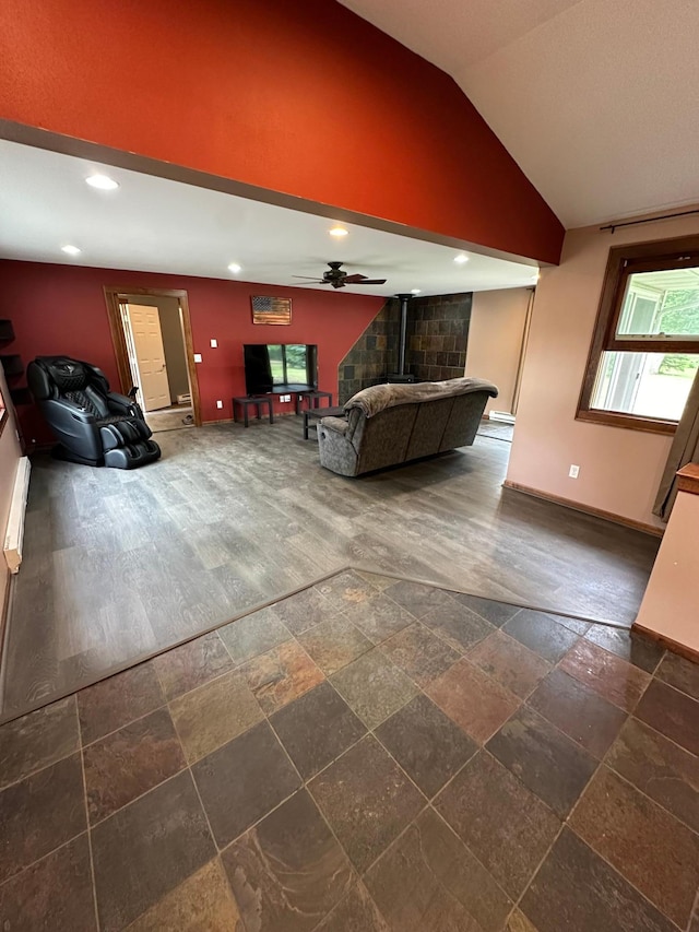 unfurnished living room with a wood stove, vaulted ceiling, ceiling fan, and dark wood-type flooring