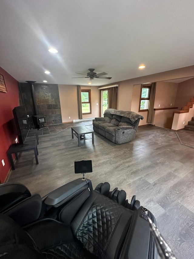 living room with a wood stove, ceiling fan, and hardwood / wood-style floors