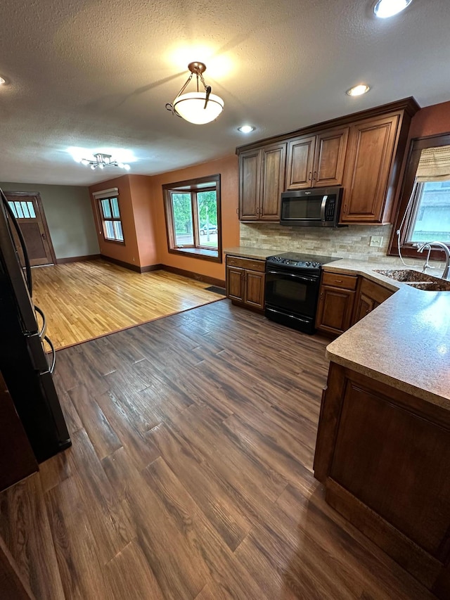921 11th St N, Mountain Lake, MN 56159 - kitchen featuring a sink, dark wood finished floors, baseboards, black electric range oven, and backsplash