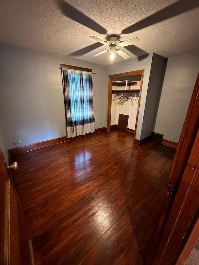 unfurnished bedroom with a textured ceiling, dark hardwood / wood-style flooring, ceiling fan, and a closet