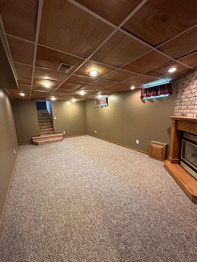 basement with a brick fireplace and carpet flooring