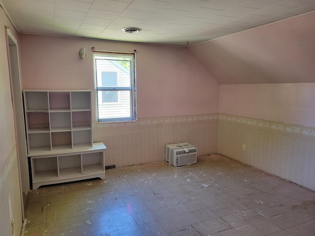 additional living space featuring tile patterned floors, an AC wall unit, and vaulted ceiling