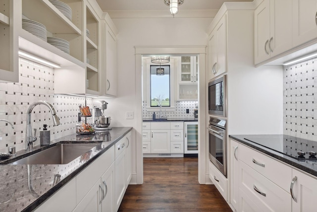 kitchen featuring decorative backsplash, stainless steel appliances, sink, white cabinets, and hanging light fixtures