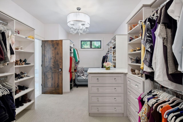 walk in closet with light colored carpet and an inviting chandelier