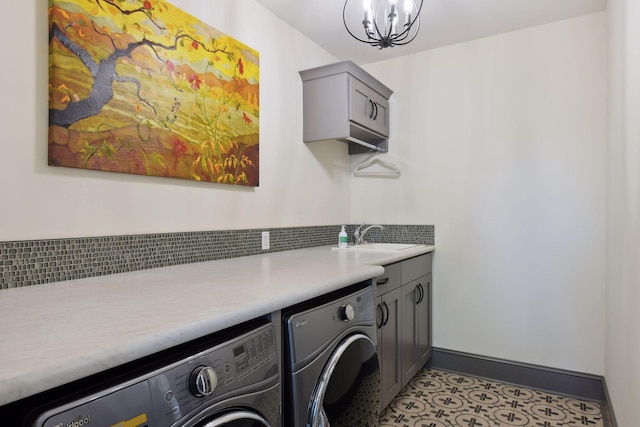 washroom with washing machine and clothes dryer, a chandelier, sink, and cabinets