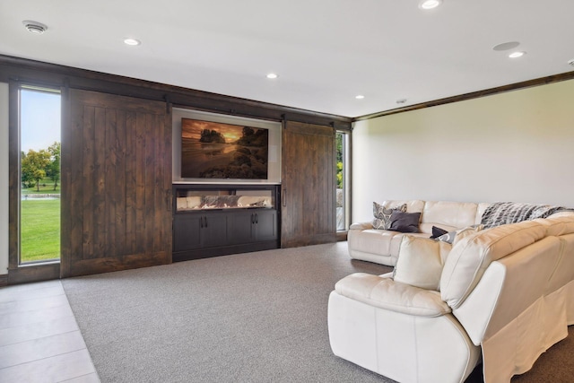 living room with a barn door, light tile patterned flooring, and crown molding