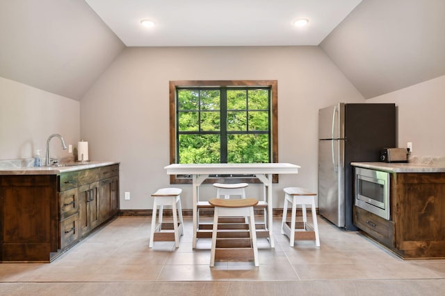 kitchen with dark brown cabinets, sink, stainless steel appliances, and vaulted ceiling