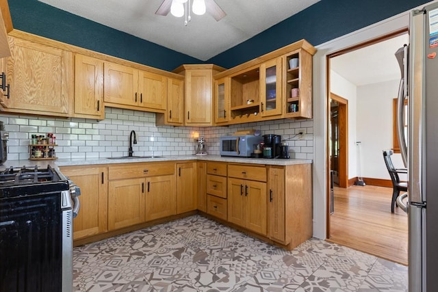 kitchen featuring light wood-type flooring, tasteful backsplash, sink, appliances with stainless steel finishes, and ceiling fan