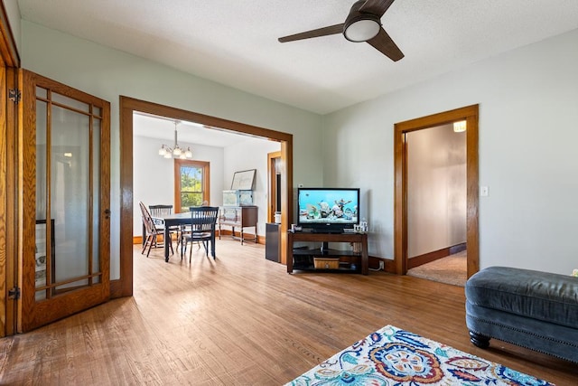 living room featuring wood-type flooring and ceiling fan with notable chandelier