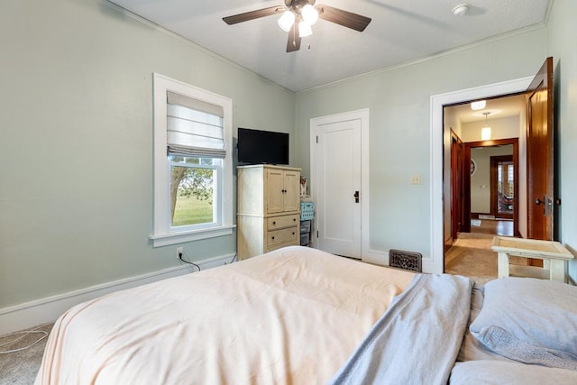 carpeted bedroom with ornamental molding and ceiling fan