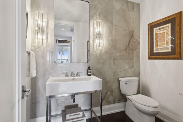 bathroom with sink, tile walls, and toilet