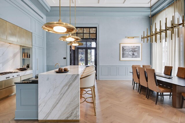 kitchen featuring blue cabinets, crown molding, pendant lighting, a breakfast bar area, and light parquet flooring