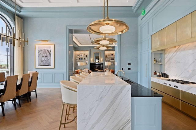 kitchen with pendant lighting, dark stone counters, light parquet floors, crown molding, and sink