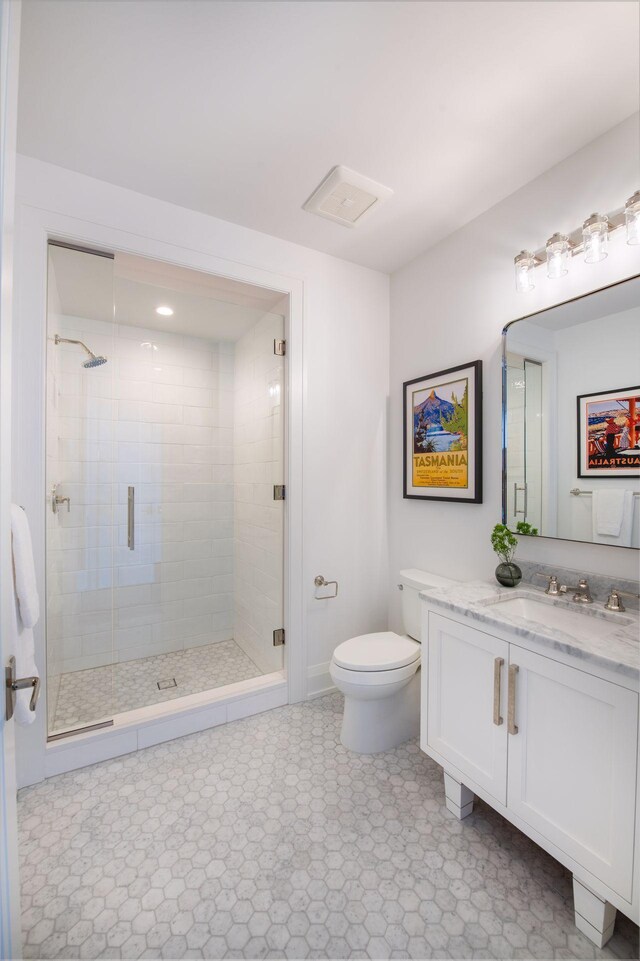 bathroom featuring vanity, toilet, and a shower with shower door