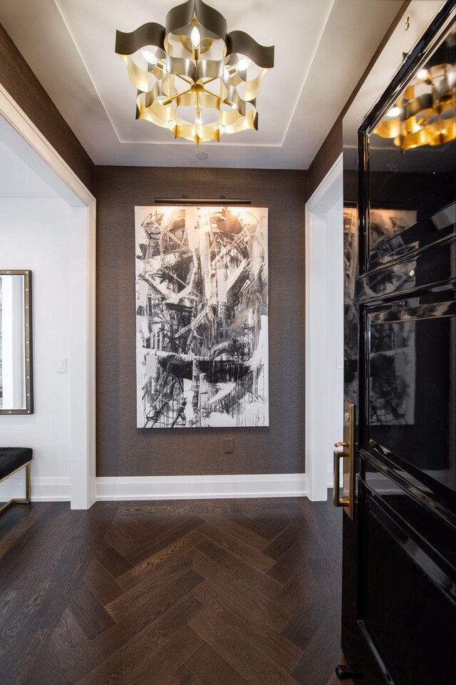 dining space with dark parquet flooring and an inviting chandelier