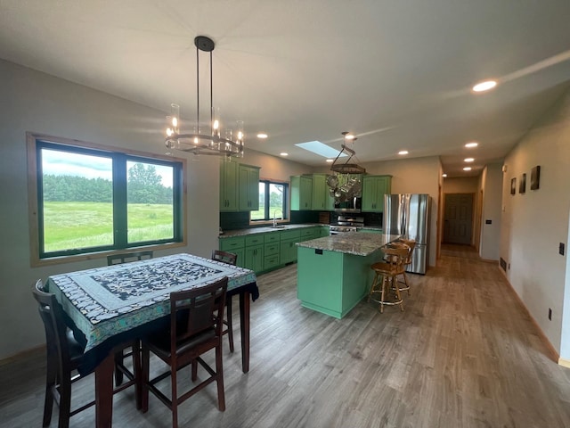 kitchen featuring a center island, sink, stainless steel appliances, green cabinets, and light hardwood / wood-style flooring