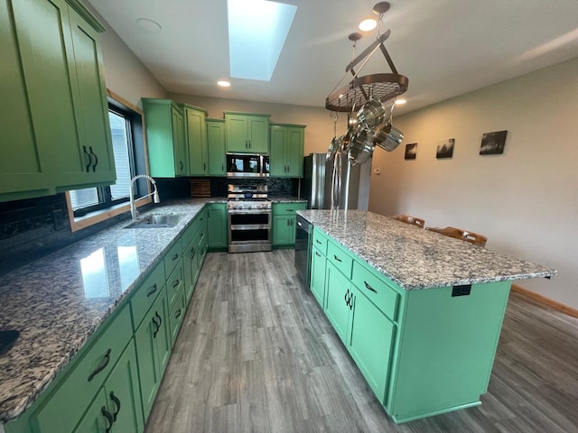 kitchen with a skylight, a center island, green cabinets, and appliances with stainless steel finishes