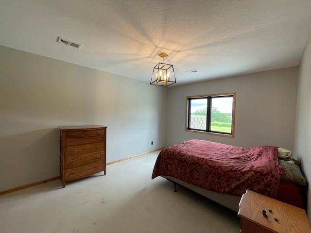 bedroom with a textured ceiling, light carpet, and an inviting chandelier