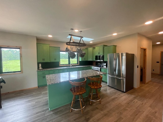 kitchen featuring stone counters, a kitchen breakfast bar, light wood-type flooring, appliances with stainless steel finishes, and a kitchen island