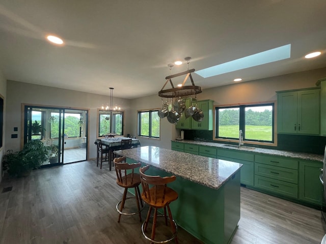 kitchen featuring green cabinets, sink, a skylight, a kitchen island, and wood-type flooring