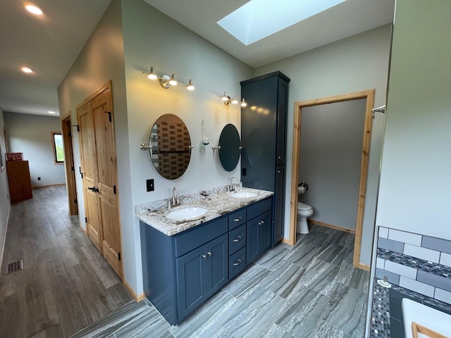 bathroom featuring a skylight, vanity, wood-type flooring, and toilet