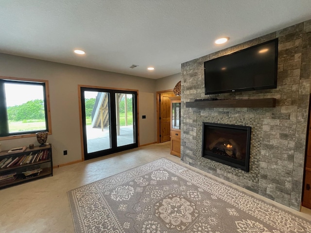 living room featuring plenty of natural light, a stone fireplace, and a textured ceiling