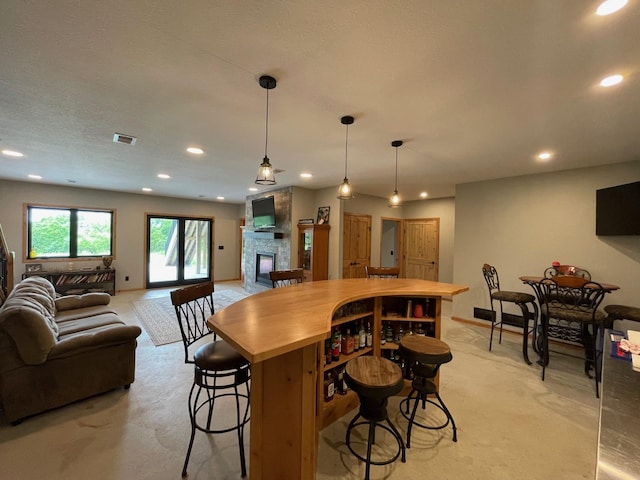 kitchen featuring pendant lighting, a textured ceiling, a fireplace, light carpet, and a breakfast bar