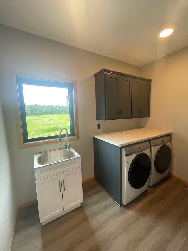 laundry room featuring cabinets, light wood-type flooring, separate washer and dryer, and sink