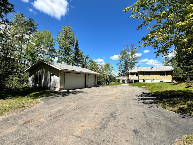 view of front of property featuring a front lawn, an outbuilding, and a garage