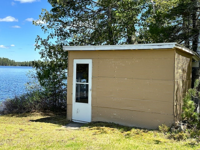 view of outbuilding with a lawn and a water view