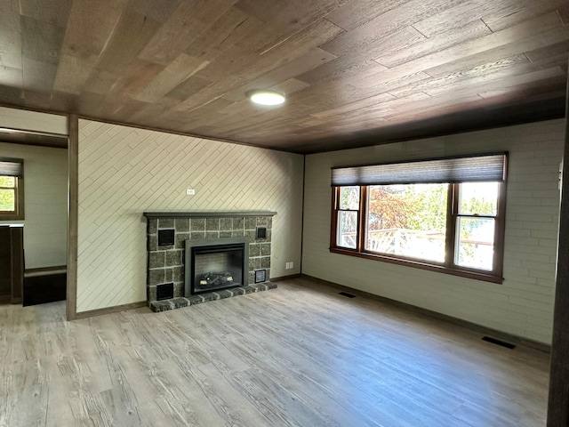 unfurnished living room featuring light hardwood / wood-style flooring, wood ceiling, wood walls, and a fireplace