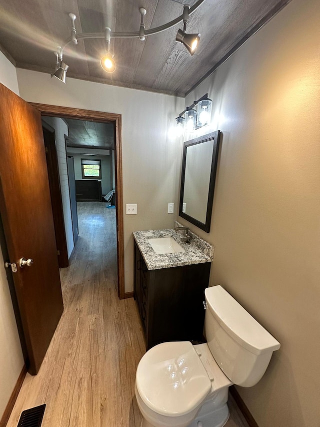 bathroom featuring rail lighting, hardwood / wood-style floors, vanity, and toilet