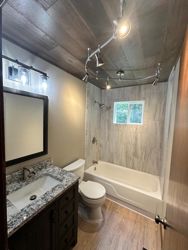 full bathroom with vanity, tiled shower / bath, hardwood / wood-style flooring, and toilet