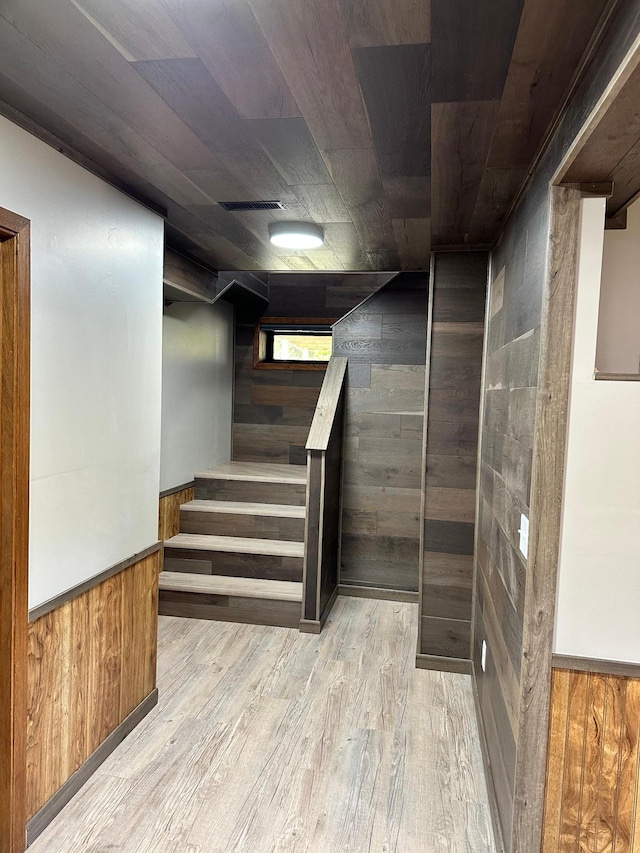 basement with light wood-type flooring and wood walls