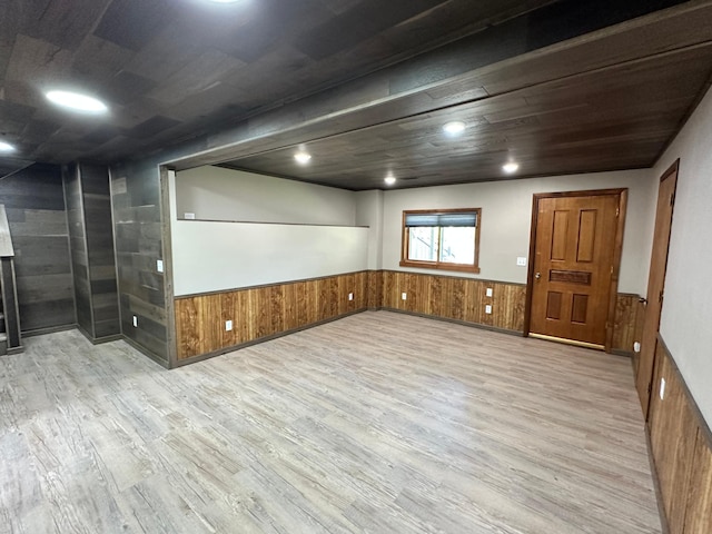 spare room featuring light hardwood / wood-style flooring and wood walls