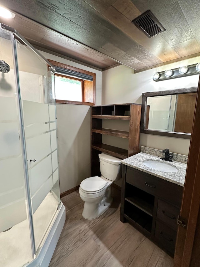 bathroom featuring wood-type flooring, vanity, toilet, and a shower with shower door