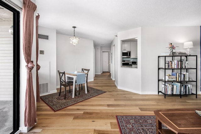 dining room with wood-type flooring, vaulted ceiling, and a textured ceiling