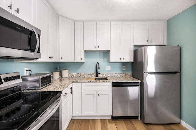 kitchen featuring white cabinetry, light hardwood / wood-style floors, stainless steel appliances, and sink