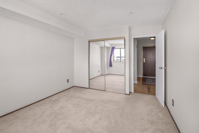 unfurnished bedroom featuring a closet, a textured ceiling, and light carpet