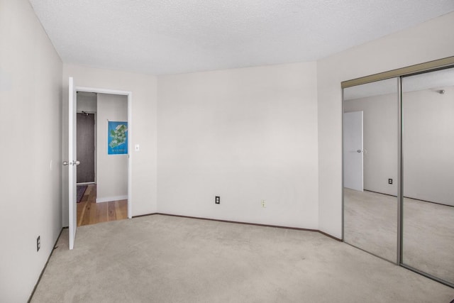 unfurnished bedroom featuring a closet, a textured ceiling, and light colored carpet