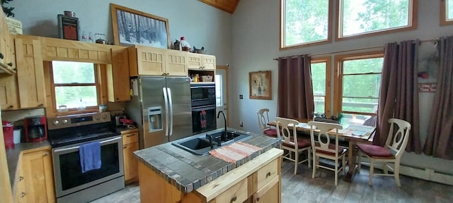 kitchen with tile countertops, sink, a center island, stainless steel appliances, and light brown cabinets